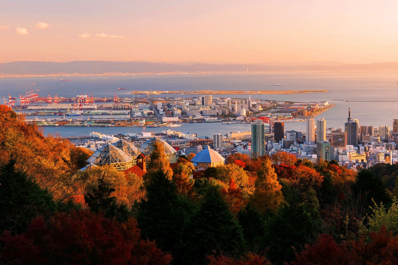Herbstlicher Aussichtspunkt über Kobe Hafen mit buntem Laub und Stadtpanorama