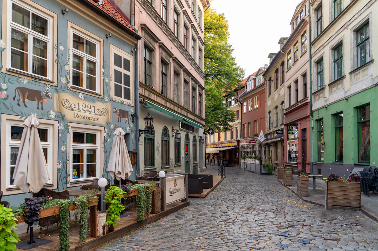 Ruhige Kopfsteinpflasterstraße in Rigas Altstadt mit historischen Häusern Cafés und Sommerterrassen Lettland Städtereise