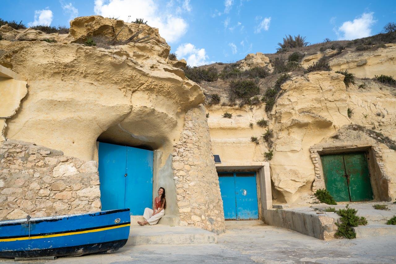 Felsige Bootshäuser mit bunten Türen und kleinem Boot auf Gozo Hörverstehen üben am Meer