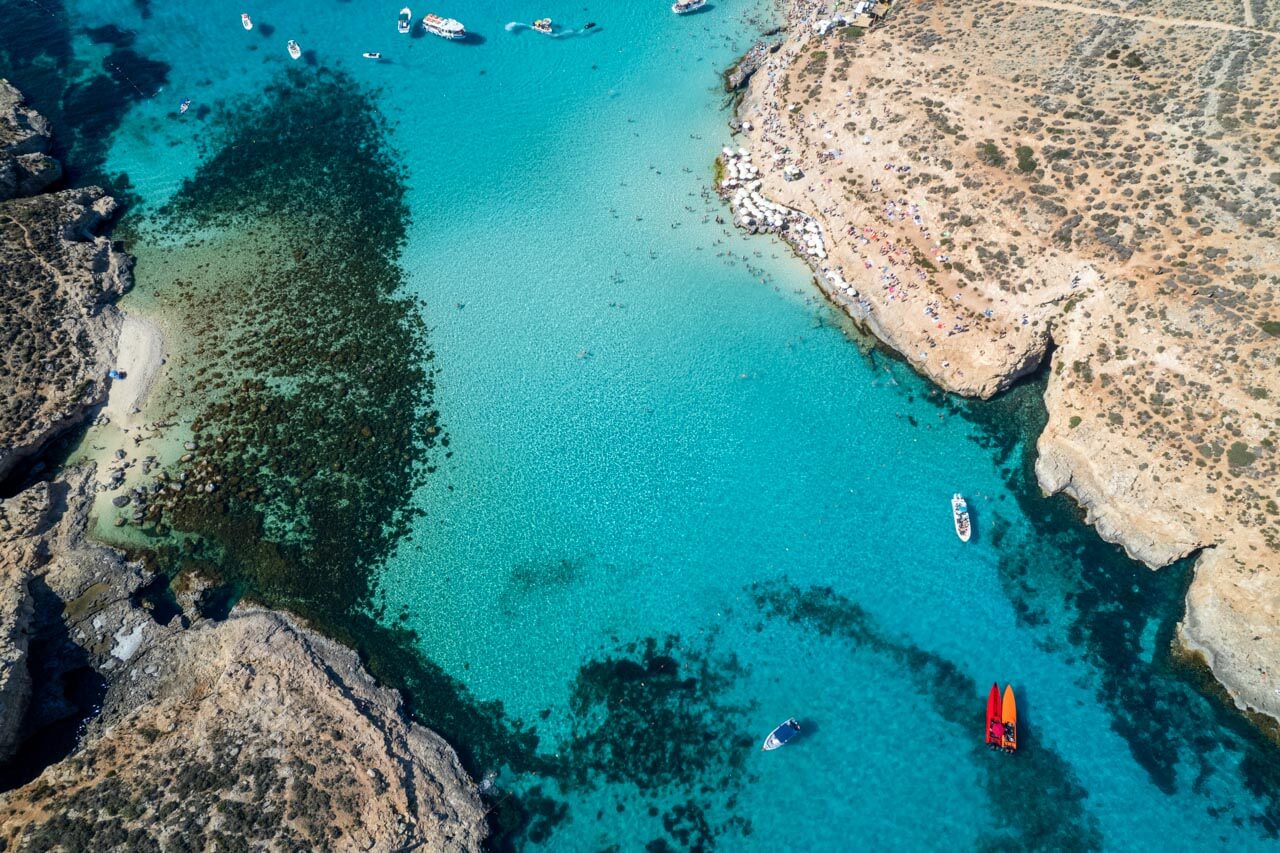 Türkisblaue Bucht mit Felsentor und ruhendem Segelboot. Hörverstehen mit Reisegeschichten stärken