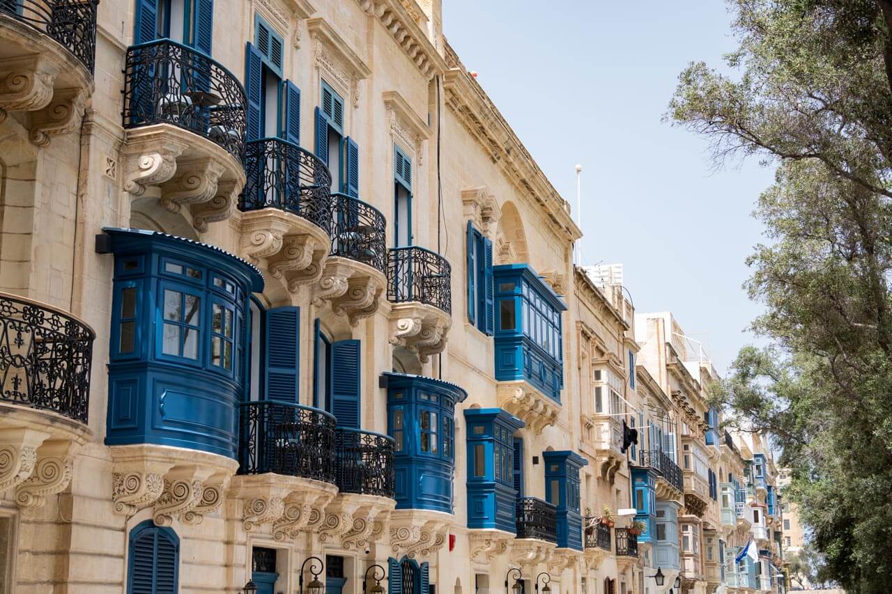 Reihe traditioneller Sandsteinhäuser mit blauen Balkonen, Architektur erkunden. Grammatik im Kontext üben.