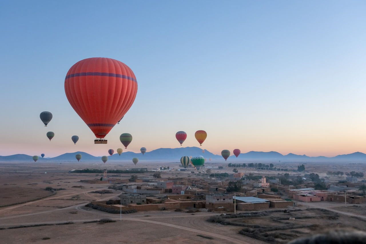 Heißluftballons über Stadt bei Sonnenaufgang, Leseverstehen und Beschreiben im Arabischkurs üben.