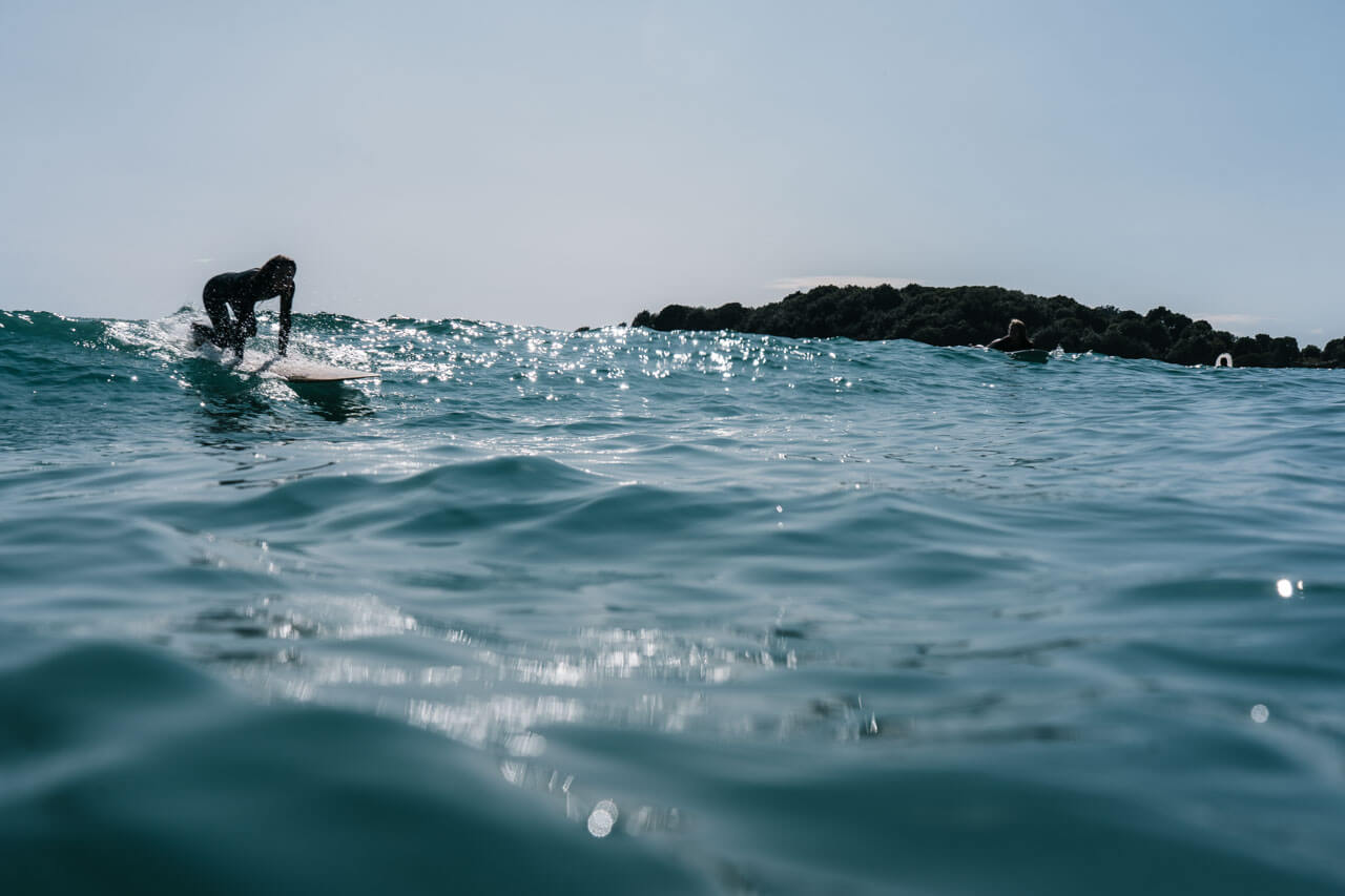Surfer richtet sich auf einer glitzernden Welle auf, Hörverstehen üben am Strand nach dem Kurs.