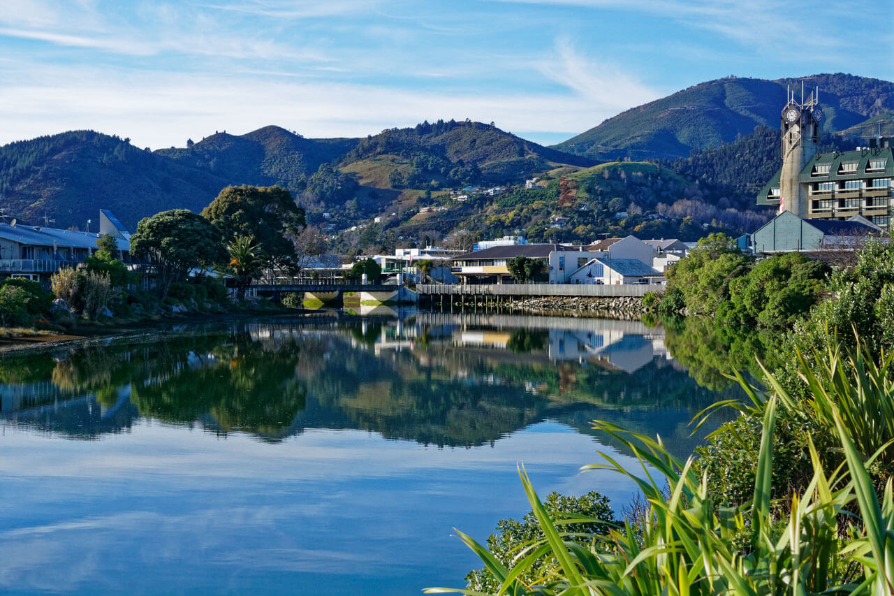 Spiegelnde Uferpromenade mit Bergen im Hintergrund, Sprachreise in einer Hafenstadt.