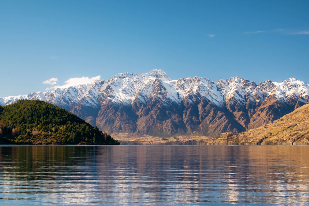 Schneegipfel spiegeln im ruhigen See, Aussprache verbessern beim Spaziergang.