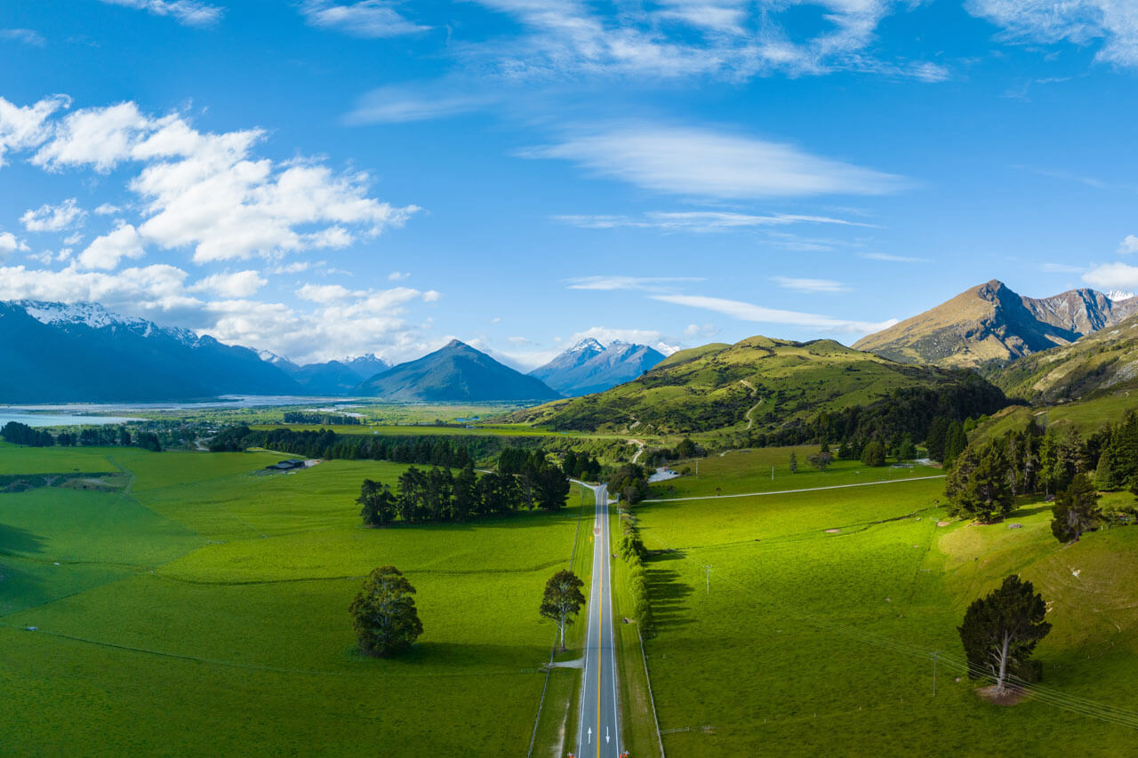 Weite Ebene mit Straße zu schneebedeckten Gipfeln, Grammatik trainieren unterwegs.