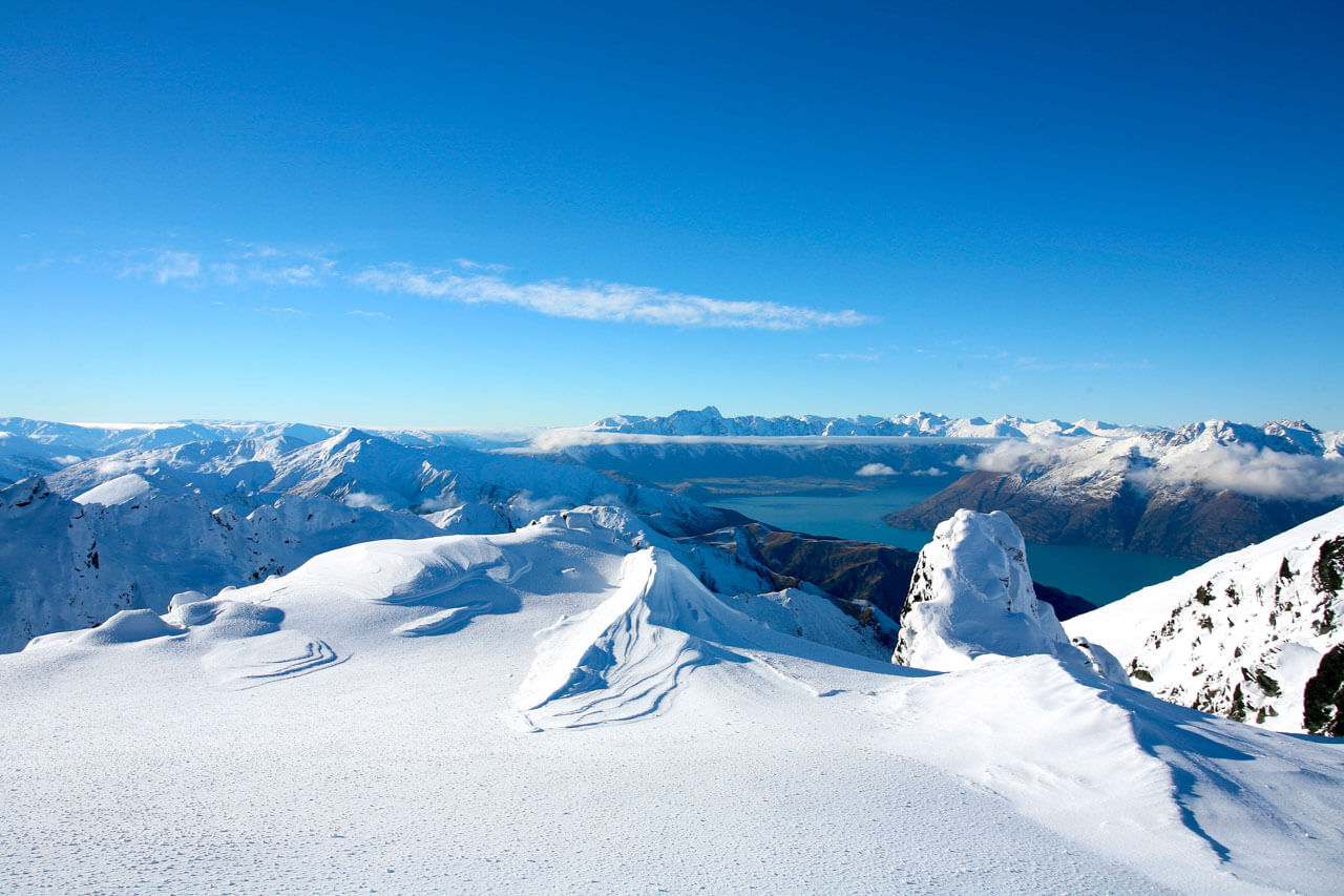 Verschneite Bergkämme und tiefer See in der Ferne, Sprachkurs im Winter.
