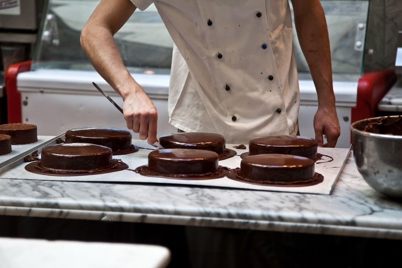 Konditor glasiert Schokoladentorten, Wortschatz zu Backen und Rezepten im Deutschkurs.