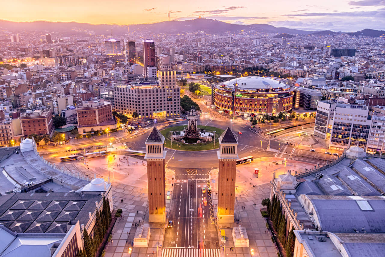 Plaza de España bei Dämmerung, Zwillingstürme, Kreisverkehr und beleuchtete Stadt.