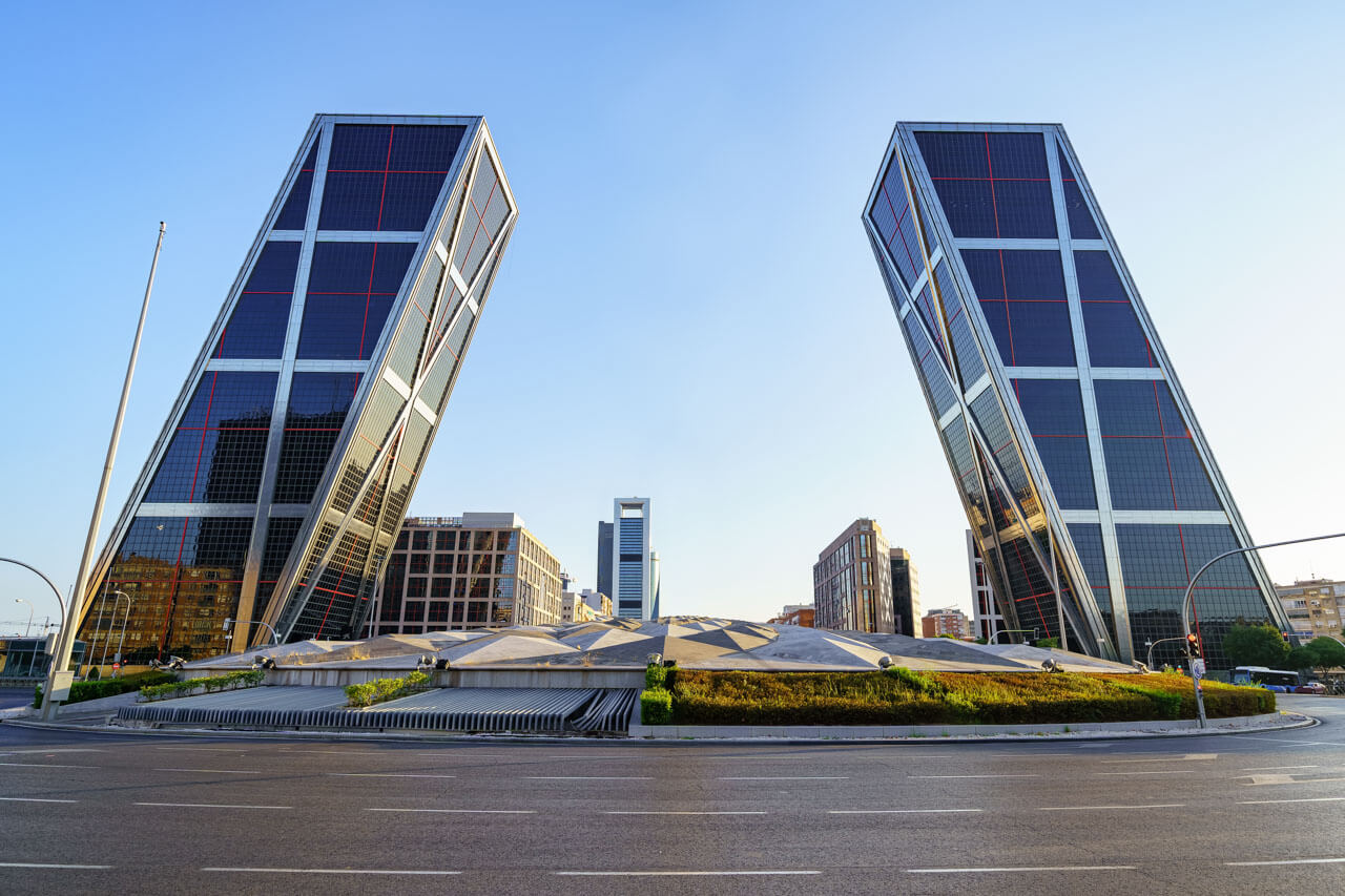 Die schräg geneigten KIO-Towers an der Plaza de Castilla, moderne Hochhäuser vor blauem Himmel.