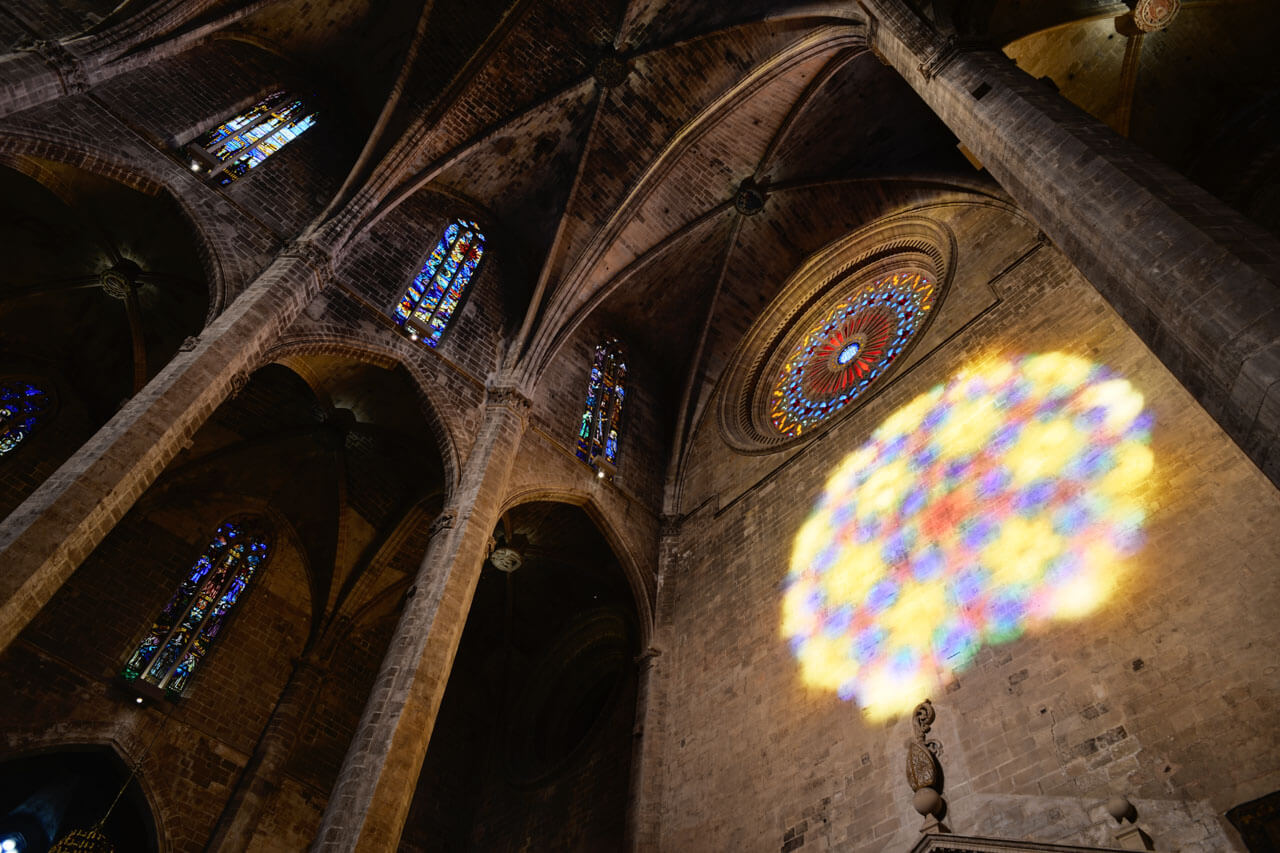 Palma-Kathedrale „La Seu“ innen: farbiges Rosenfenster wirft Lichtmosaik an die Wand.