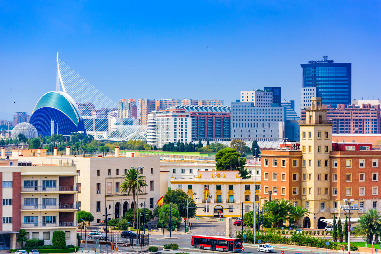 Panorama von Valencia mit der Ciudad de las Artes y las Ciencias, modernen Brücken und historischer Bebauung unter blauem Himmel.
