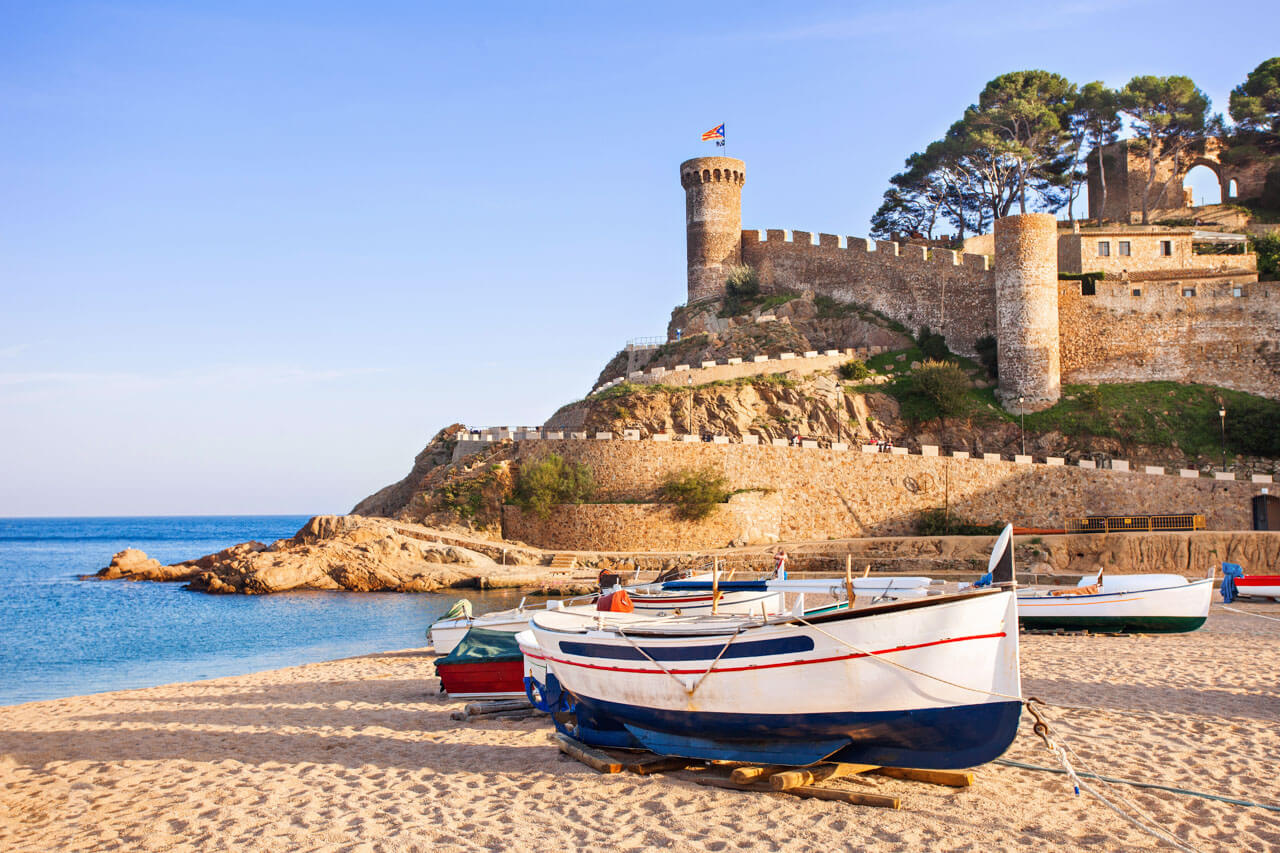 Boote am Strand und Burg am Felsen Küstenpause im Spanischkurs, Konversation üben am Meer.