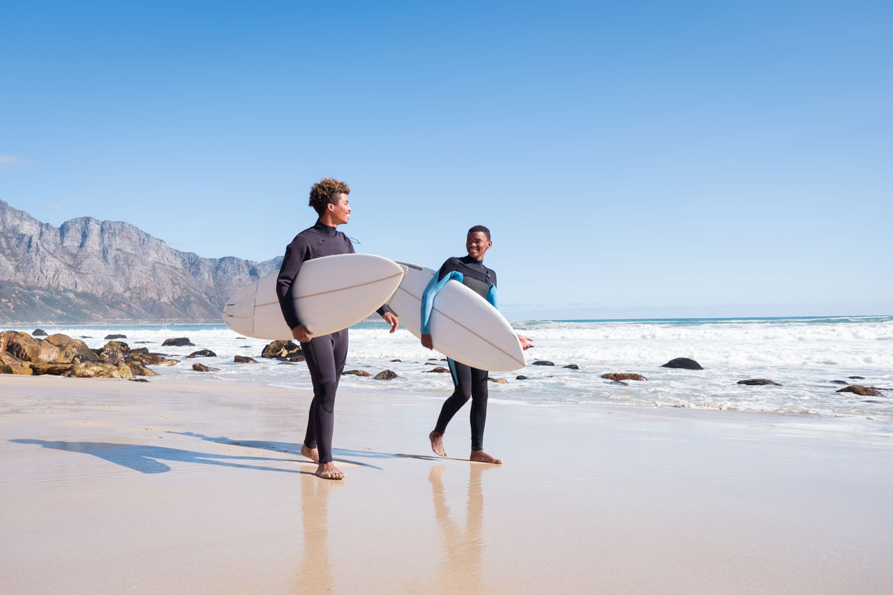 Zwei Surfer im Neopren am Strand, Konversation üben in der Pause.