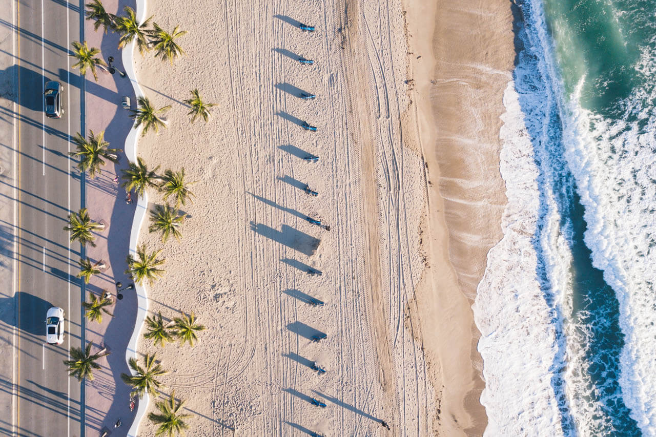 Luftaufnahme von Strand, Palmen und Wellen. Hörverstehen üben mit Meeresrauschen.