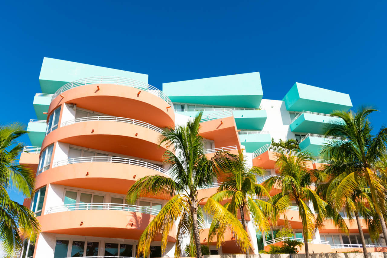 Art-déco-Fassade mit Palmen und Balkonen. Architektur erleben, Grammatik trainieren im Englischkurs.