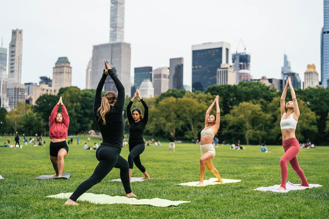 Yoga im Park vor Hochhäusern, Vokabeln rund um Freizeit und Gesundheit lernen.