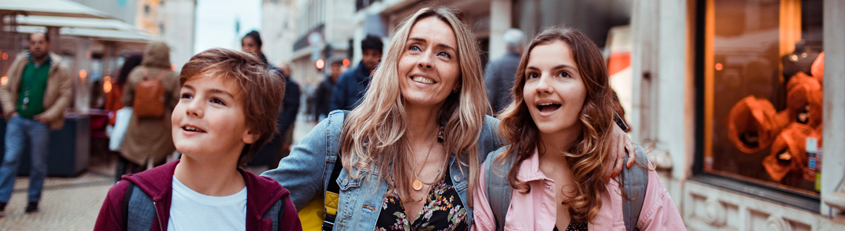 Mutter mit zwei Kindern erkundet fröhlich eine Altstadt während einer Sprachreise.