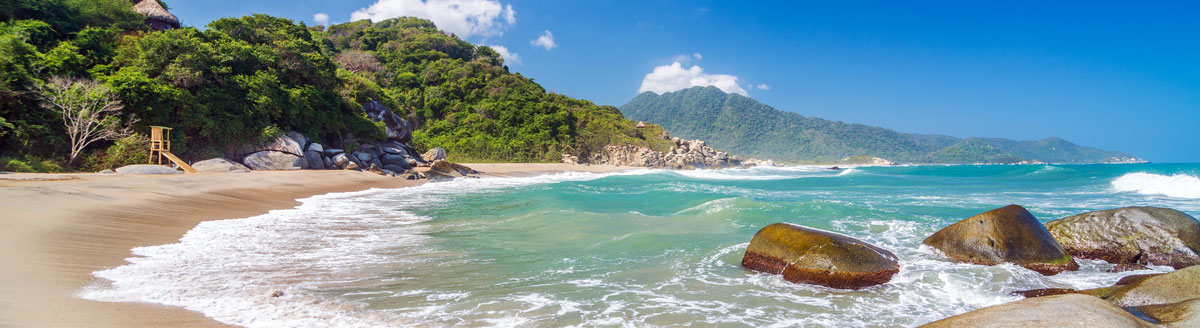 Unberührter Strand im Tayrona-Nationalpark mit Felsen, Dschungel und türkisfarbenem Meer – Sprachreise nach Kolumbien