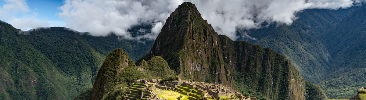 Machu Picchu in den Anden mit grün bewachsenen Bergen und Wolken – Sprachreise nach Peru