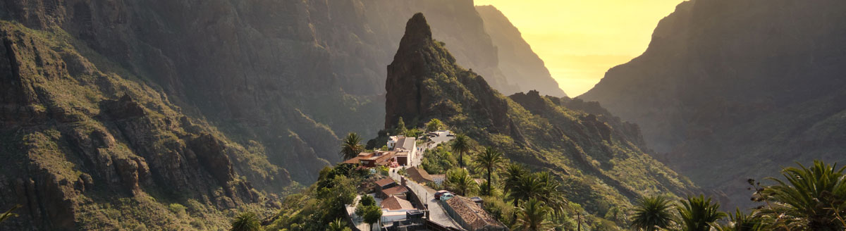 Bergkette und Bergdorf mit Palmen, viel Sonne und Ausblick aufs Meer