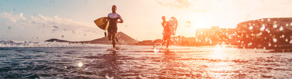 Surfer laufen am Strand von Los Angeles ins Wasser – sonnige Kulisse für Englisch-Sprachreisen an die US-Westküste